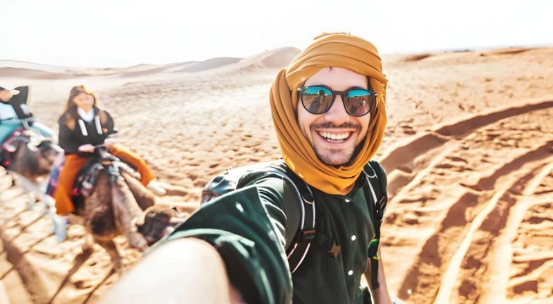 Viajero con turbante junto a camellos en el desierto